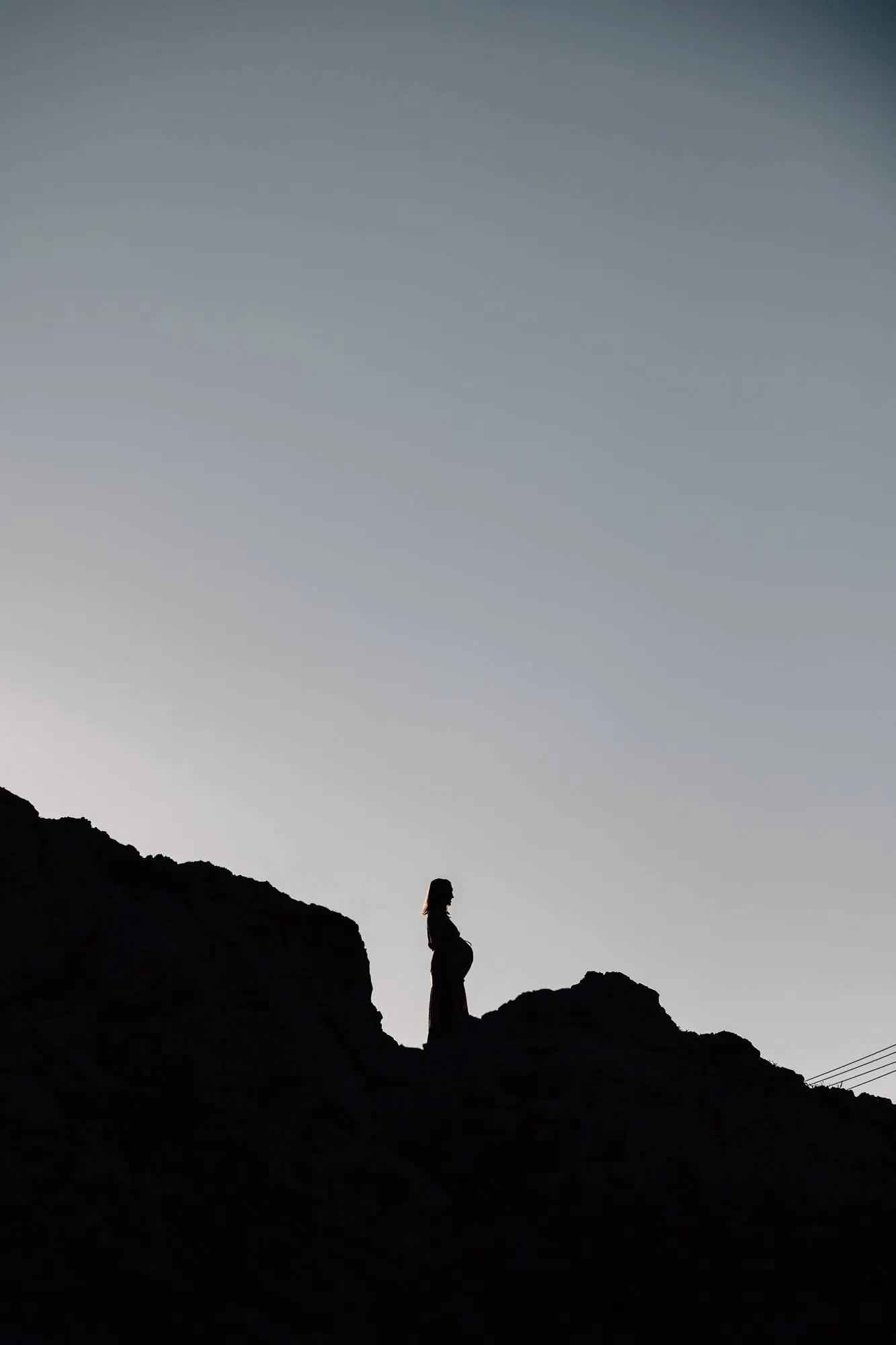 Silhouette de femme enceinte debout sur les rochers des calanques à Marseille au coucher du soleil