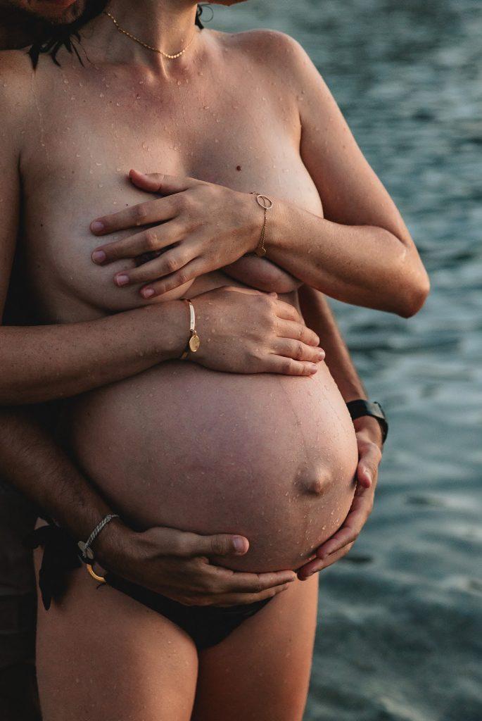 moment de tendresse d'un couple lors d'un shooting photo de grossesse dans l'eau des Calanques à Marseille