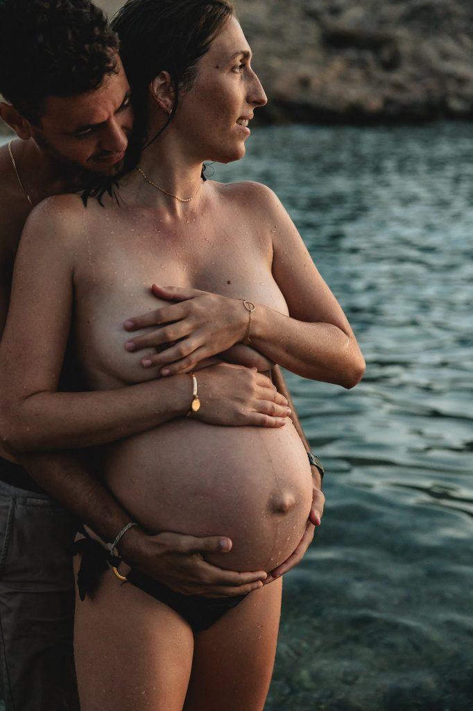 moment de tendresse d'un couple lors d'un shooting photo de grossesse dans l'eau des Goudes à Marseille