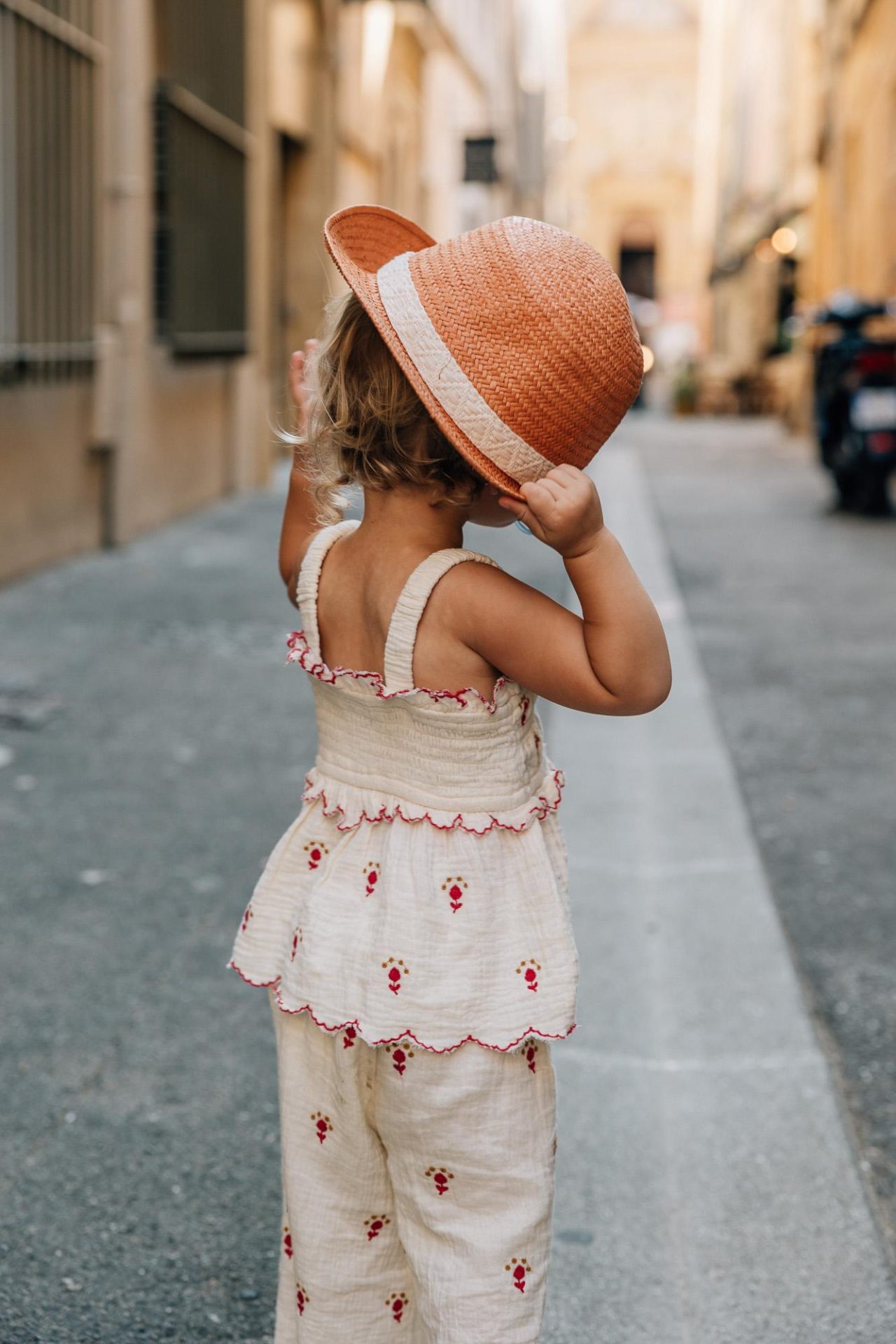 petite fille tient son chapeau dans les ruelles d'Aix-en-Provence