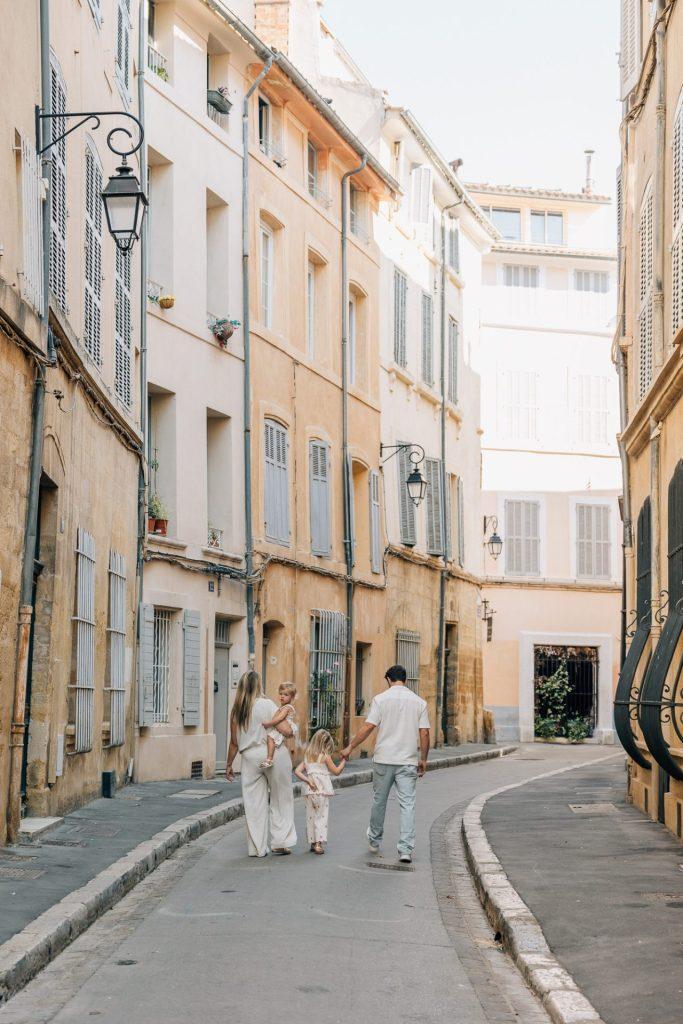 Une famille marche dans les ruelles tranquilles d'Aix-en-Provence lors d'un shooting photo en famille
