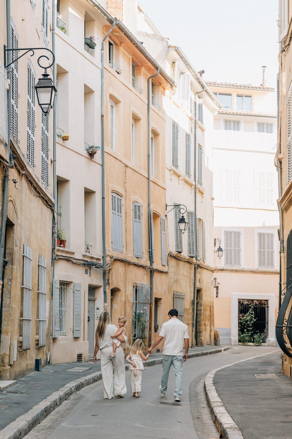 Une famille marche dans les ruelles tranquilles d'Aix-en-Provence lors d'un shooting photo en famille