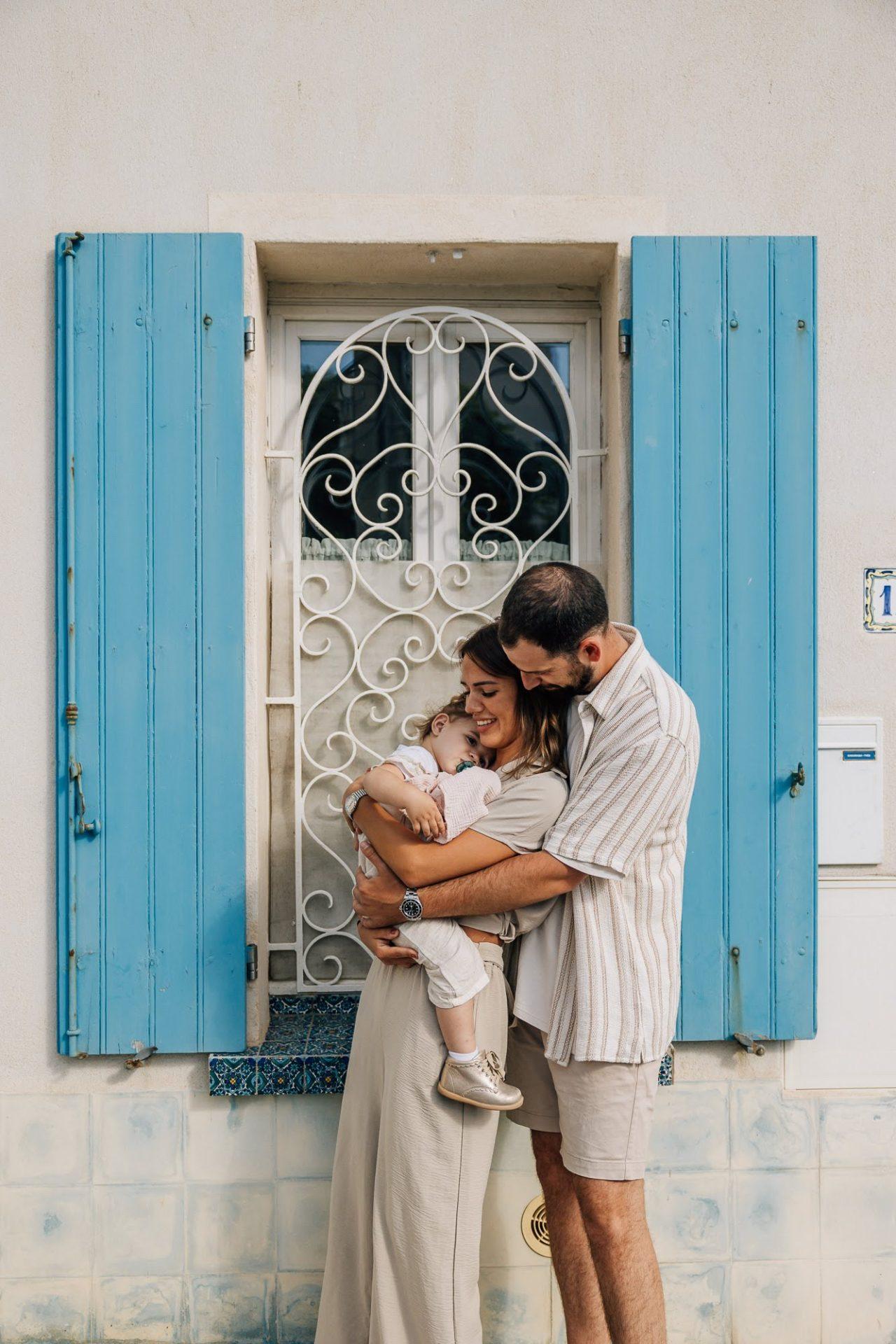 des parents et leur bébé devant des fenêtres bleues lors d'un shooting photo de famille à Malmousque à Marseille