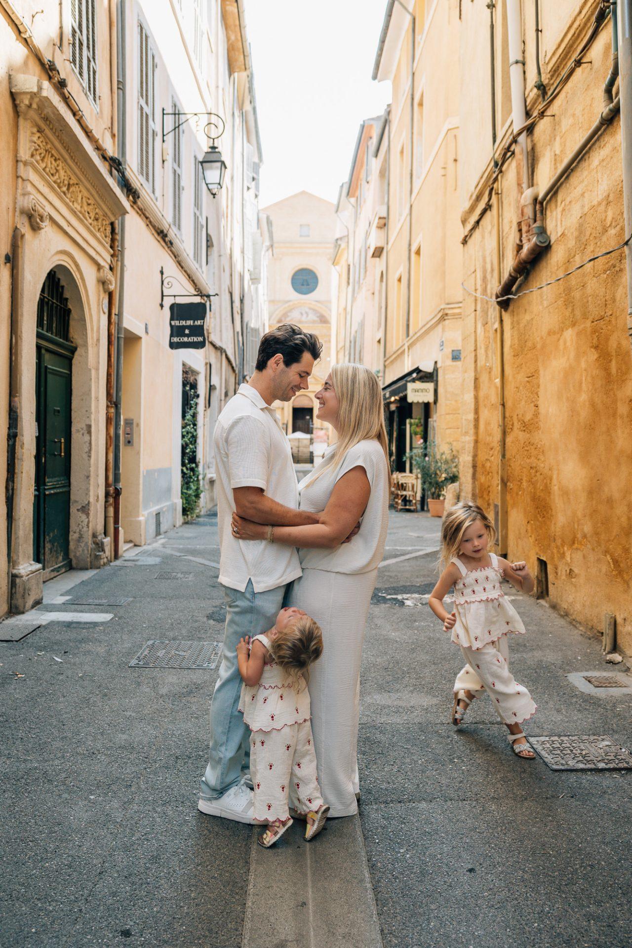 famille avec deux enfants dans une rue pavée à aix en provence façade ocre lumière douce