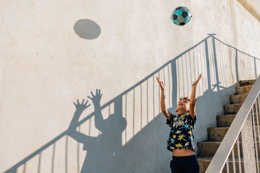 petit garçon joue au ballon dans les escaliers lors d'une séance photo de famille à la plage des Sablettes à Marseille