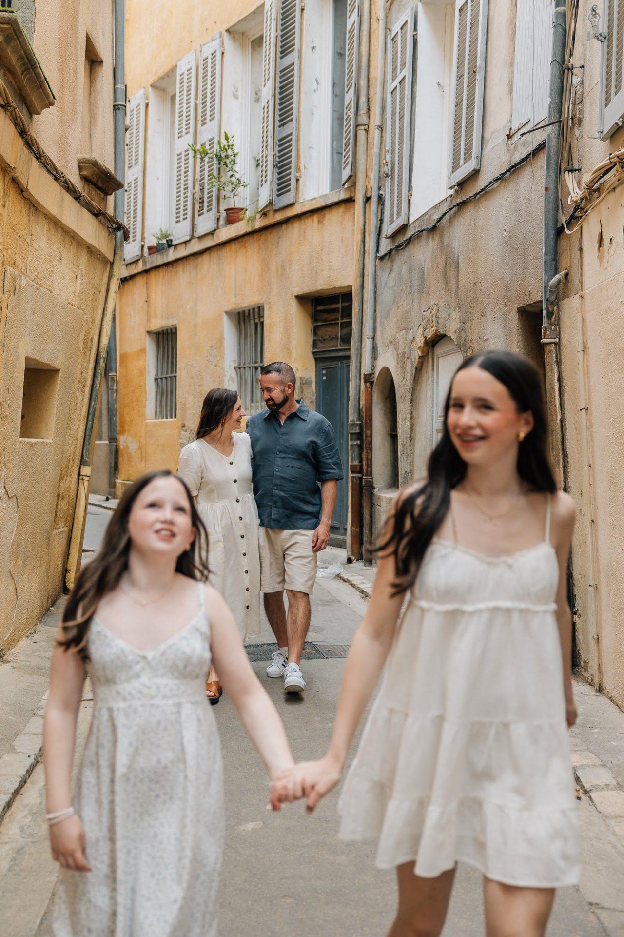 Séance photo famille marchant dans une ruelle ocre à Aix-en-Provence