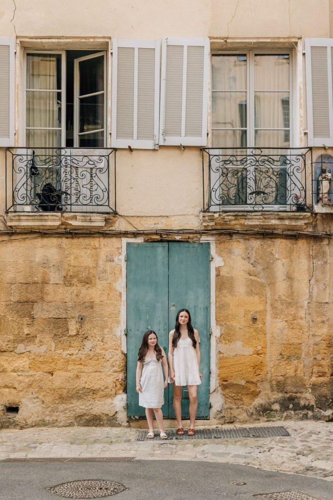 photo deux sœurs ruelle Provence porte verte mur ocre robes claires lumière douce style méditerranéen