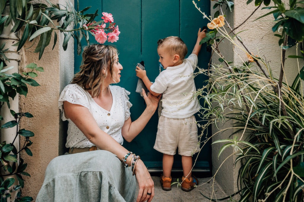 Séance photo mère et enfant à Cassis devant une porte verte et plantes méditerranéennes