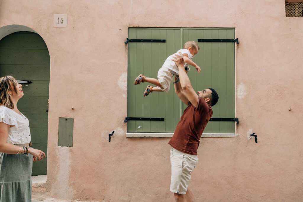 Photographe famille à Cassis – moment complice devant façade pastel et volets verts