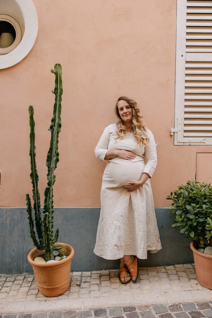 Femme enceinte devant une façade pastel à Marseille lors d’une séance photo grossesse en ville