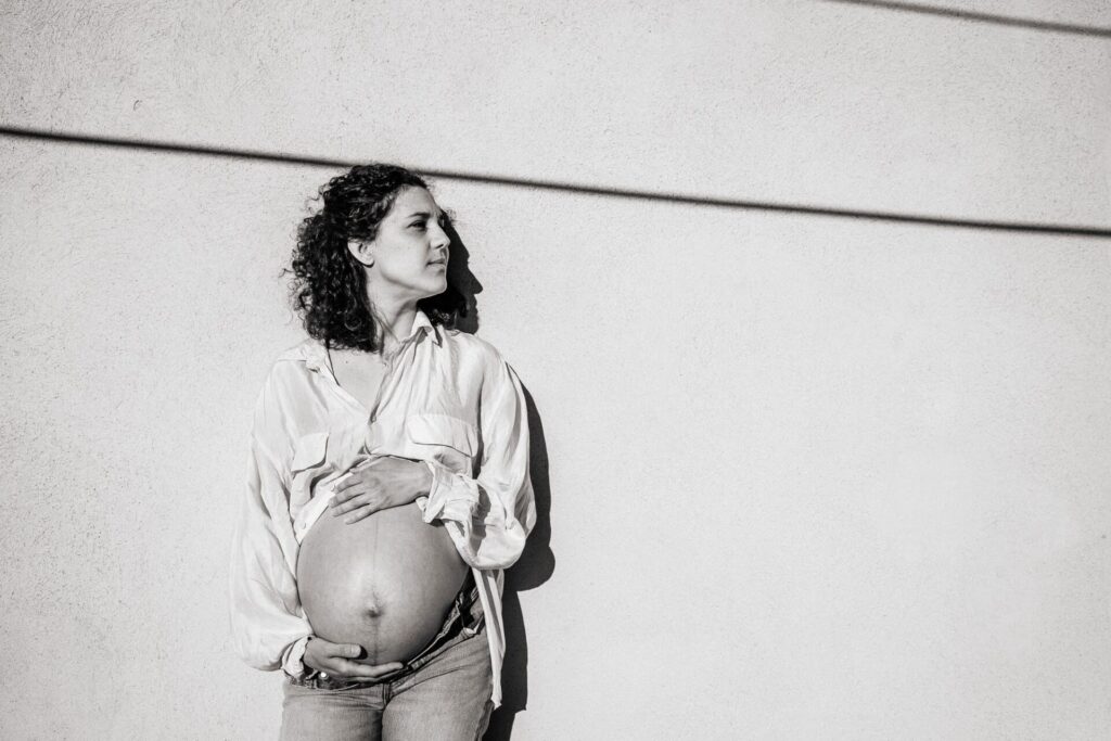 Portrait en noir et blanc d’une femme enceinte posant contre un mur graphique lors d’une séance grossesse à Malmousque, Marseille