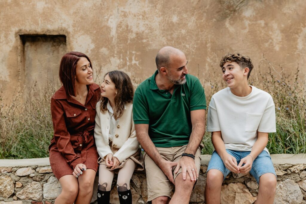 Famille assise contre un mur ocre à Marseille lors d’une séance photo famille