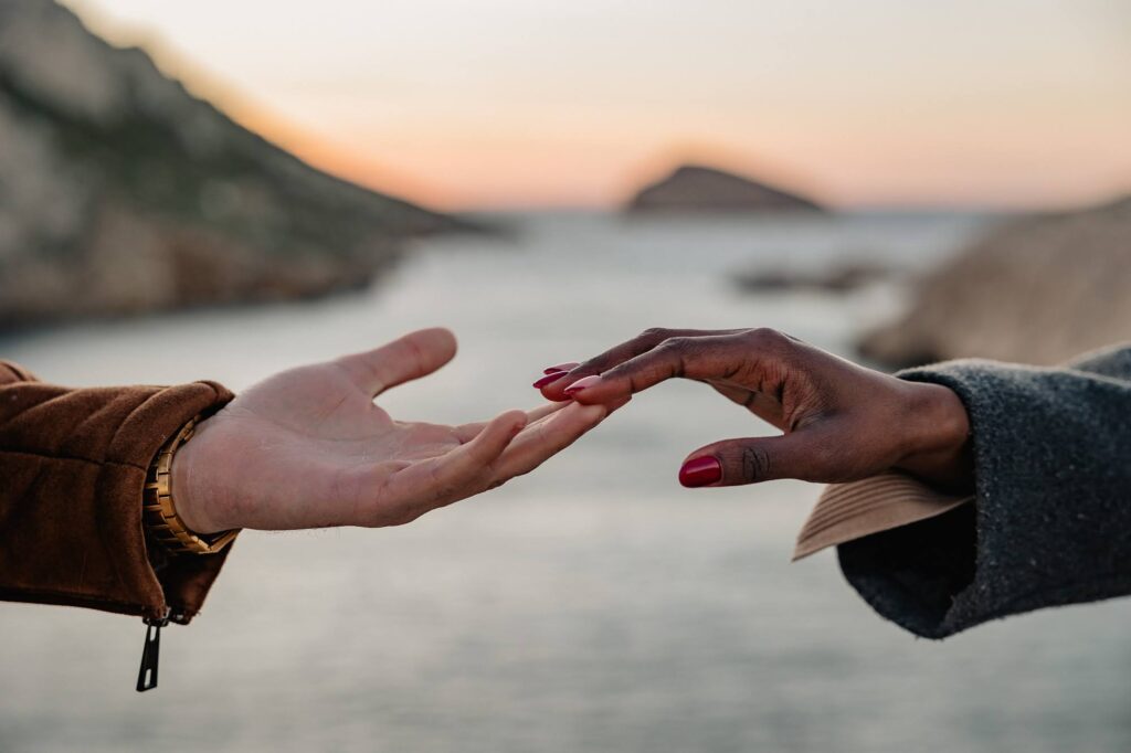 Gros plan sur des mains qui se touchent lors d'un shooting photo couple au bord de mer dans les Calanques