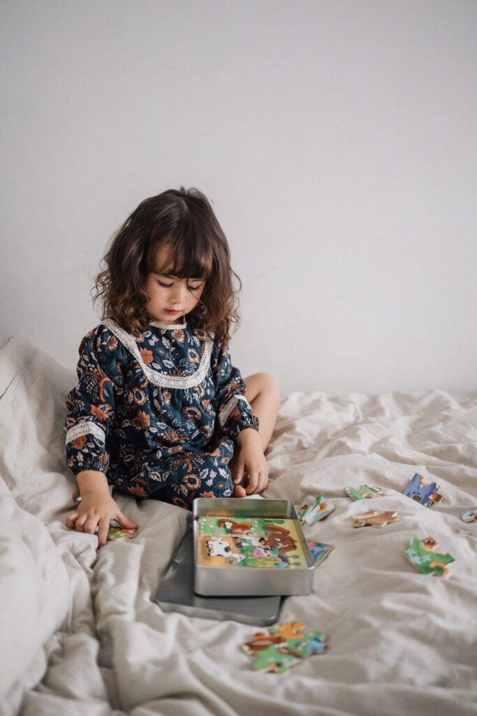 Petite fille jouant sur un lit lors d’une séance photo famille à domicile à Marseille