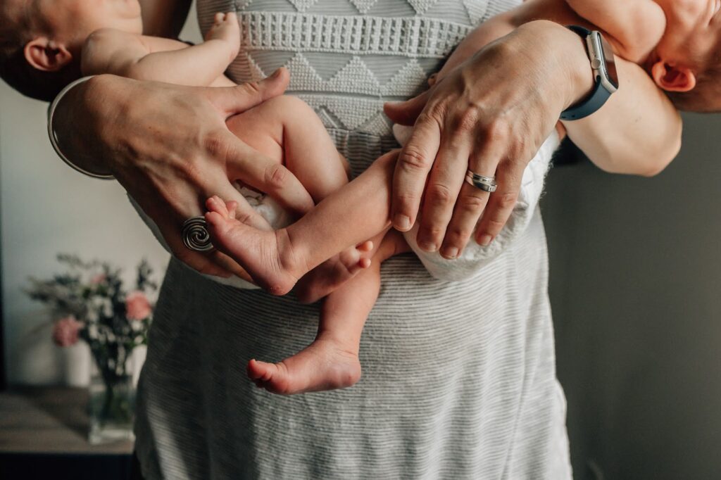 Détail des mains tenant des jumeaux nouveau-né lors d’une séance photo bébé à domicile à Marseille