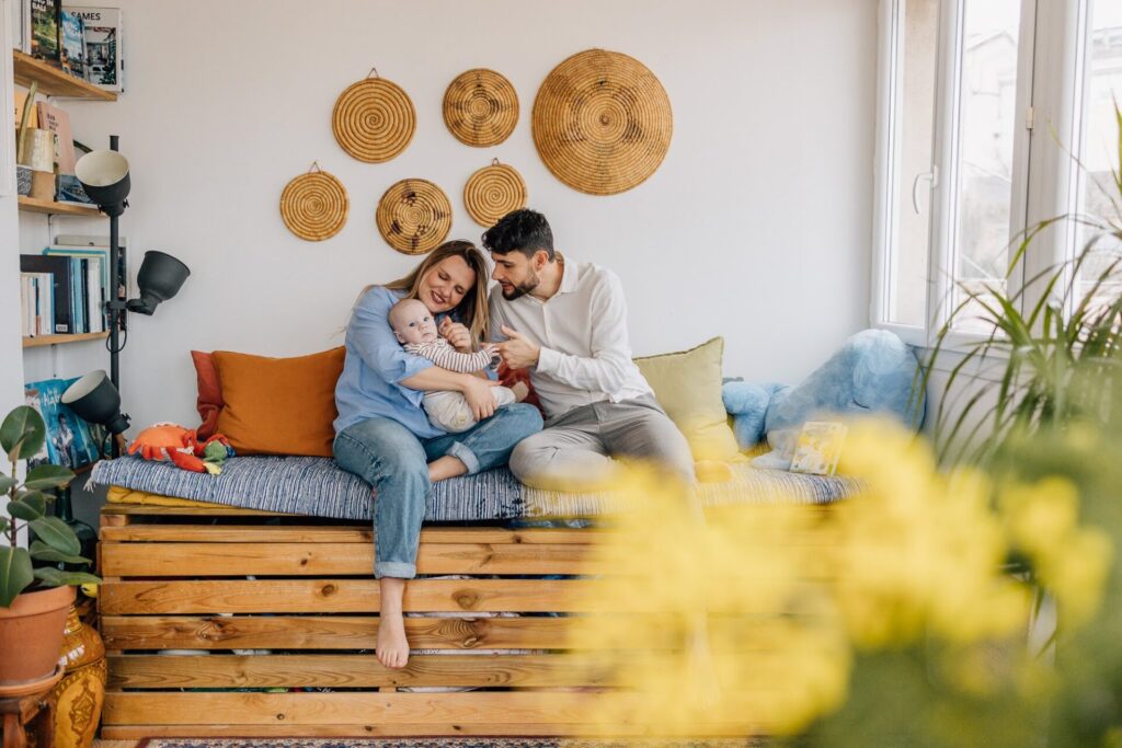 Parents assis sur un canapé avec leur bébé lors d’une séance photo bébé lifestyle à domicile à Malmousque