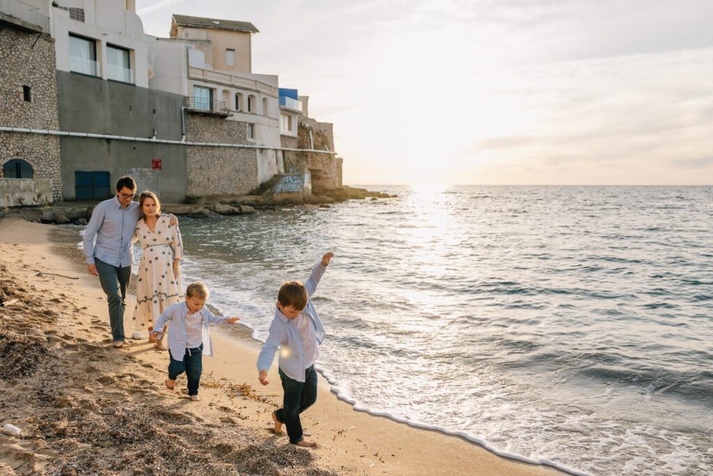 Famille marchant sur la plage au coucher du soleil lors d’une séance photo à la plage à Marseille 8e