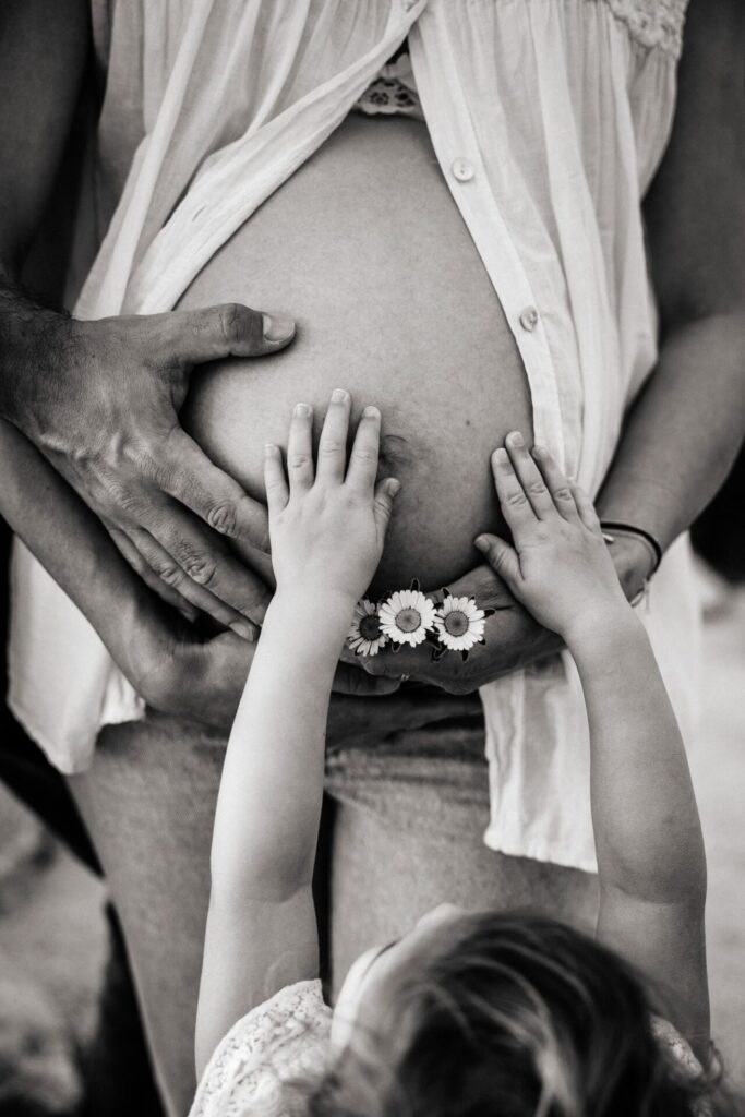 gros plan sur les mains d'une petite fille sur le ventre rond de sa maman enceinte lors d'une séance photo à Marseille