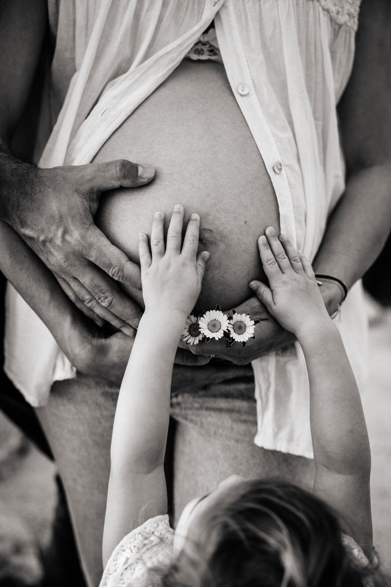 gros plan sur les mains d'une petite fille sur le ventre rond de sa maman enceinte lors d'une séance photo à Marseille