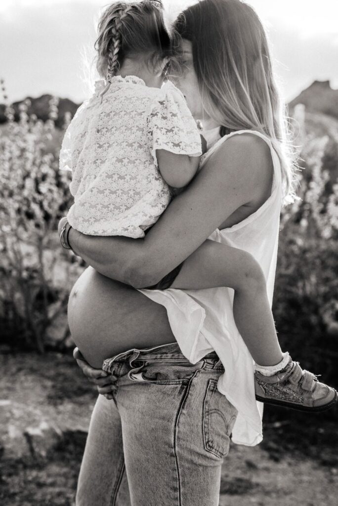 Photo en noir et blanc, maman portant sa fille, front contre front, lors d’une séance photo grossesse à Marseille