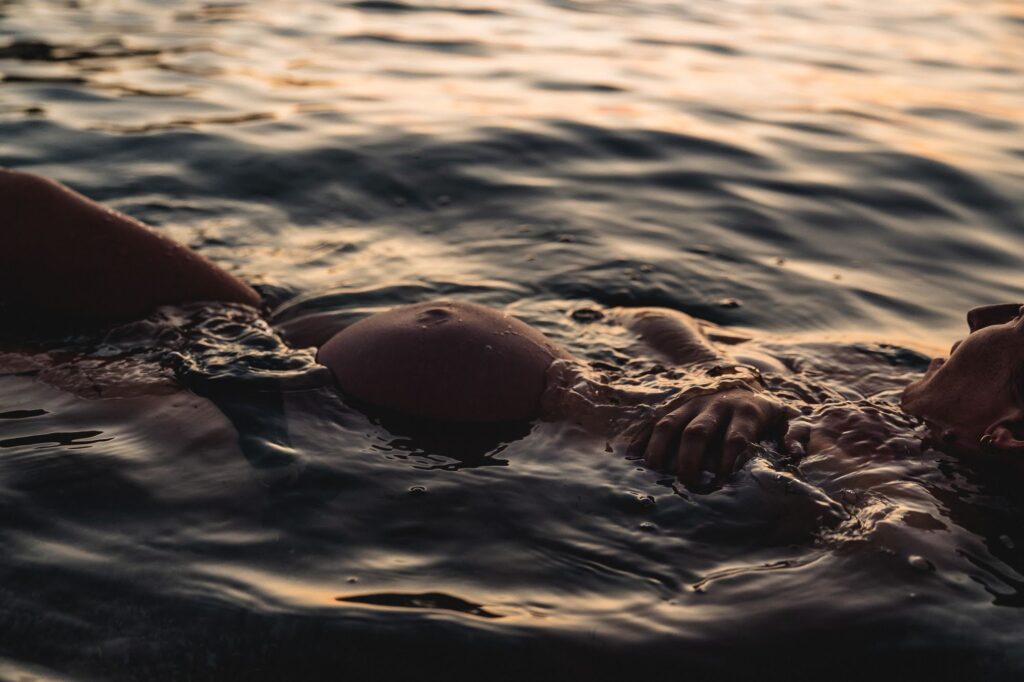 Femme enceinte dans l’eau au coucher du soleil lors d’une séance photo grossesse aux Goudes 13008 à Marseille