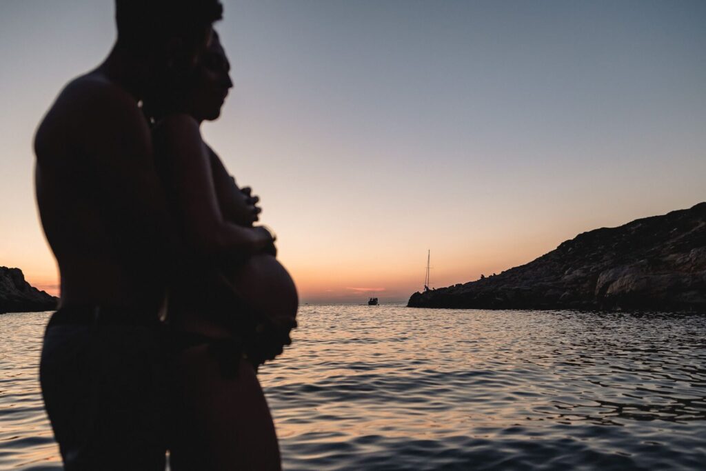 Silhouette de femme enceinte à la plage au coucher du soleil lors d’une séance photo grossesse en couple à Marseille