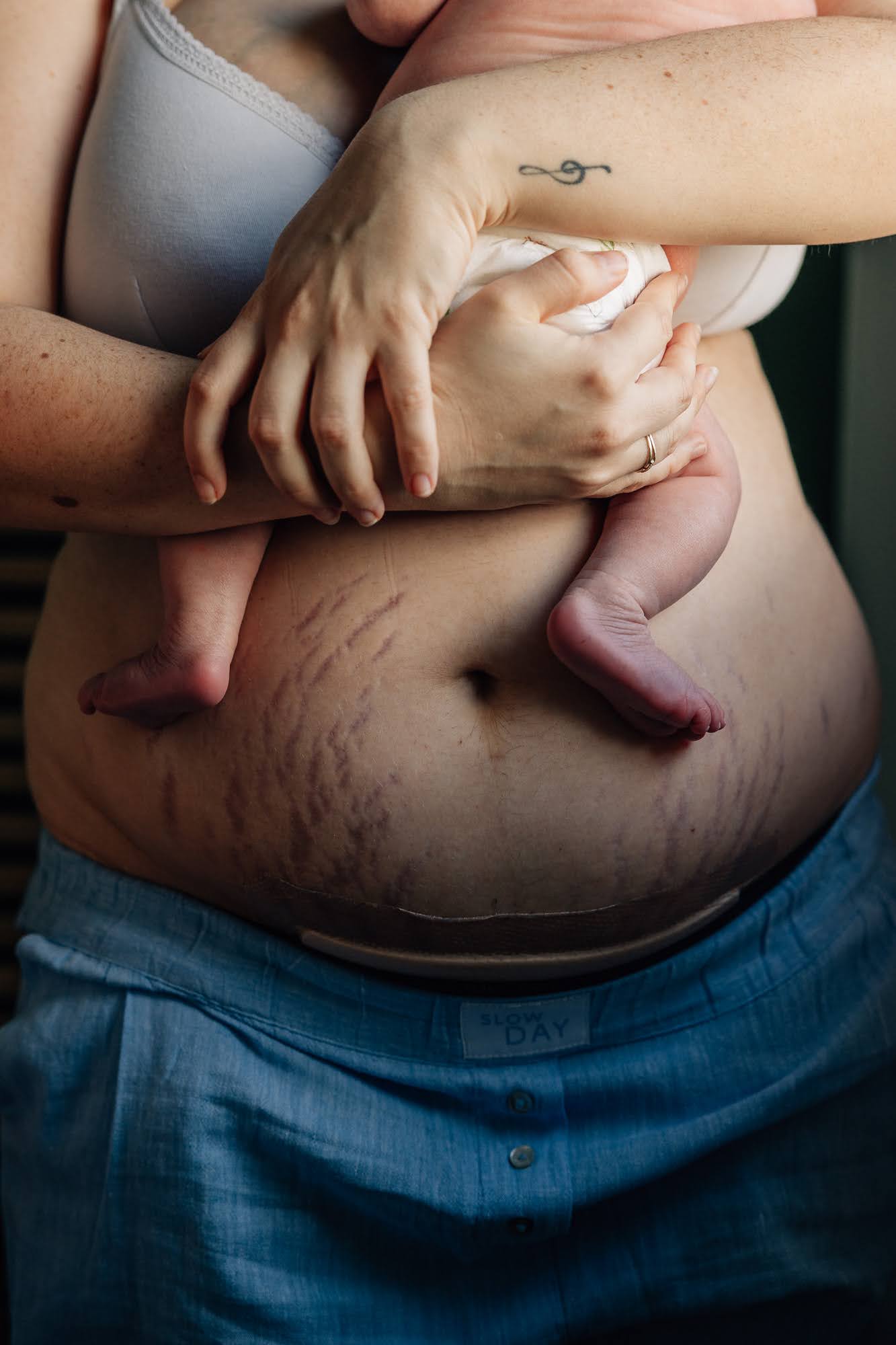 gros plan sur les pieds de nouveau-né sur le ventre de sa maman lors d'une séance photo naissance à domicile à Marseille