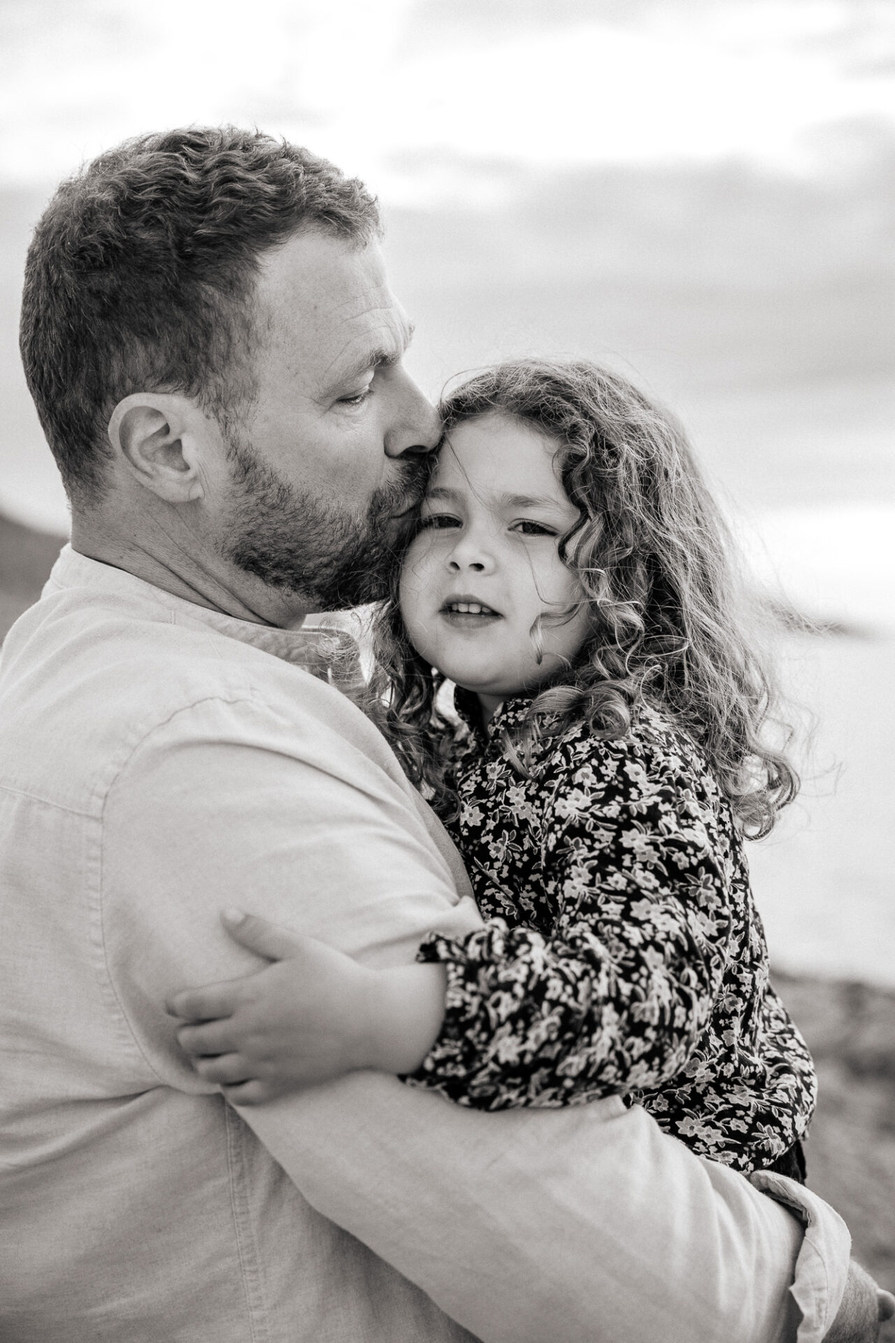 Père embrassant sa fille en bord de mer – photo en noir et blanc par une photographe professionnelle à Marseille