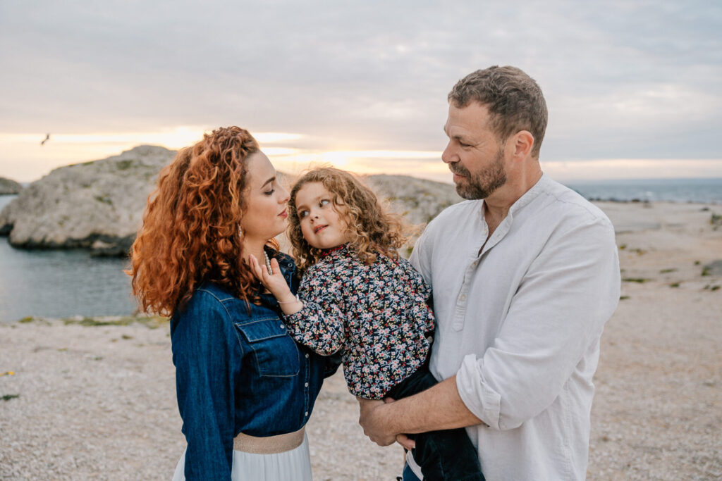 Parents avec leur enfant dans les bras lors d’une séance photo famille en extérieur dans les calanques de Marseille