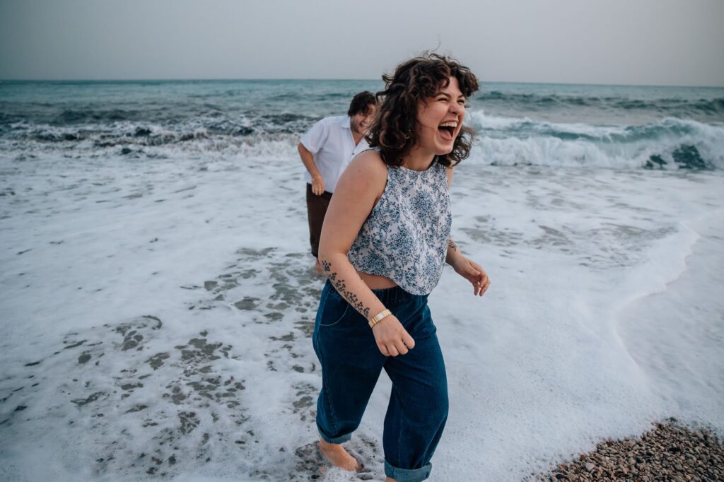 Séance photo couple riant à Cassis sur la plage avec vagues de la Méditerranée