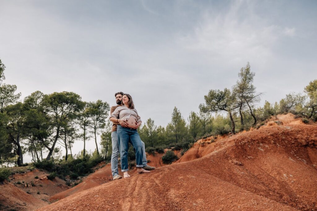 Shooting grossesse couple dans la nature en Provence sur fond de terre rouge