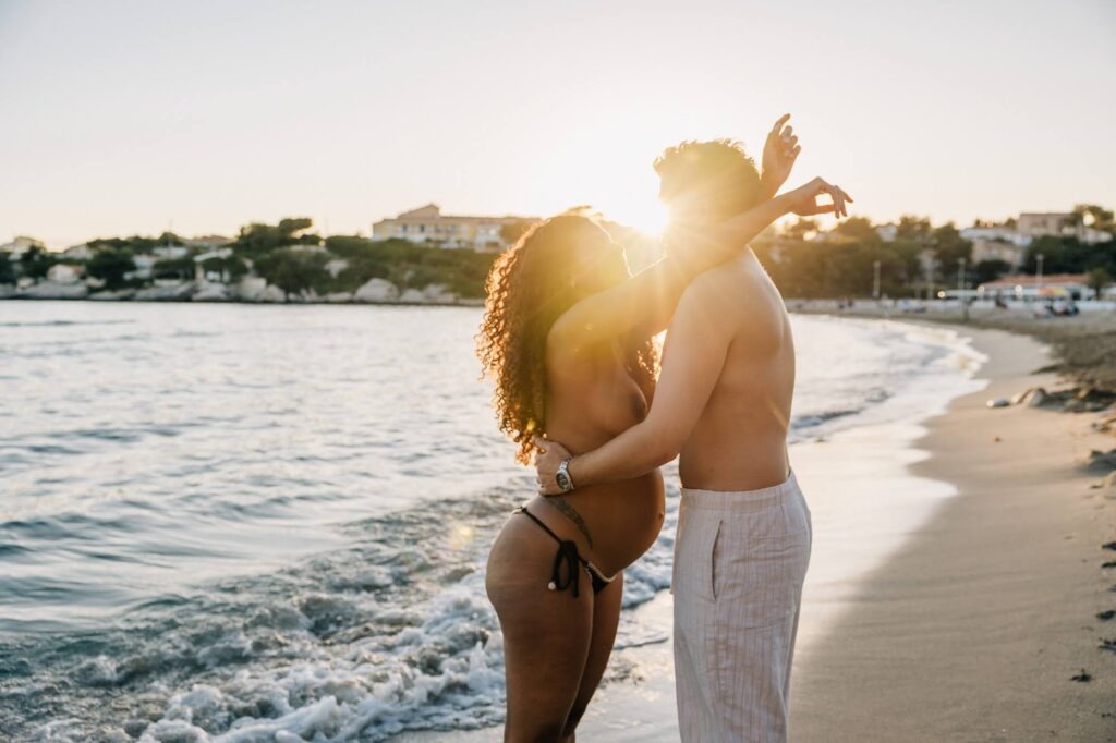 couple enlacé au bord de l’eau pendant une séance grossesse au coucher du soleil à Carry-le-Rouet