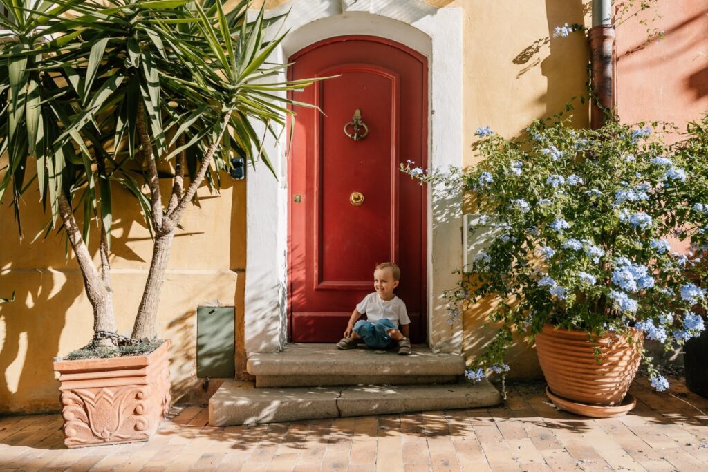 Petit garçon devant une porte colorée lors d’une séance photo dans les ruelles pastel de Cassis en Provence