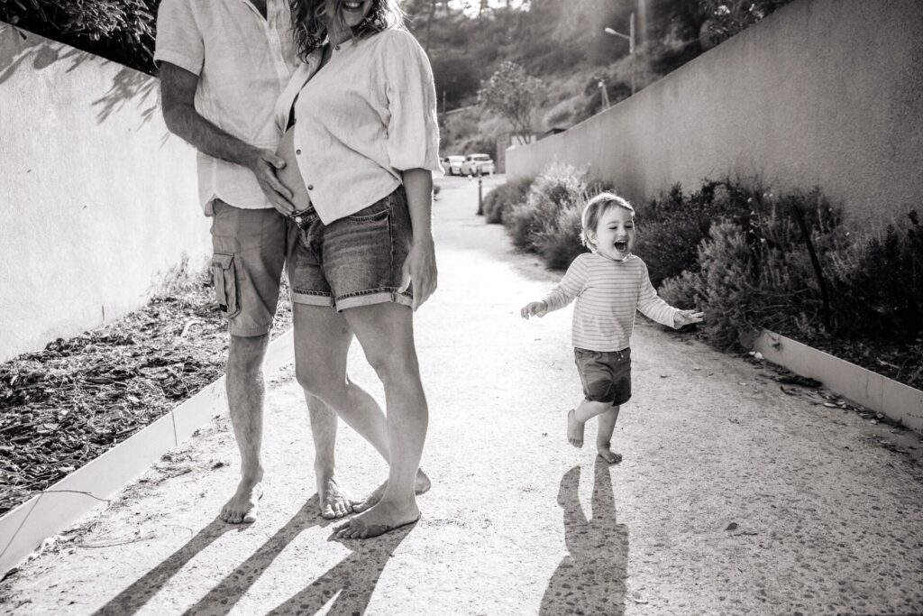 femme enceinte marchant avec son enfant pendant une séance photo grossesse en famille