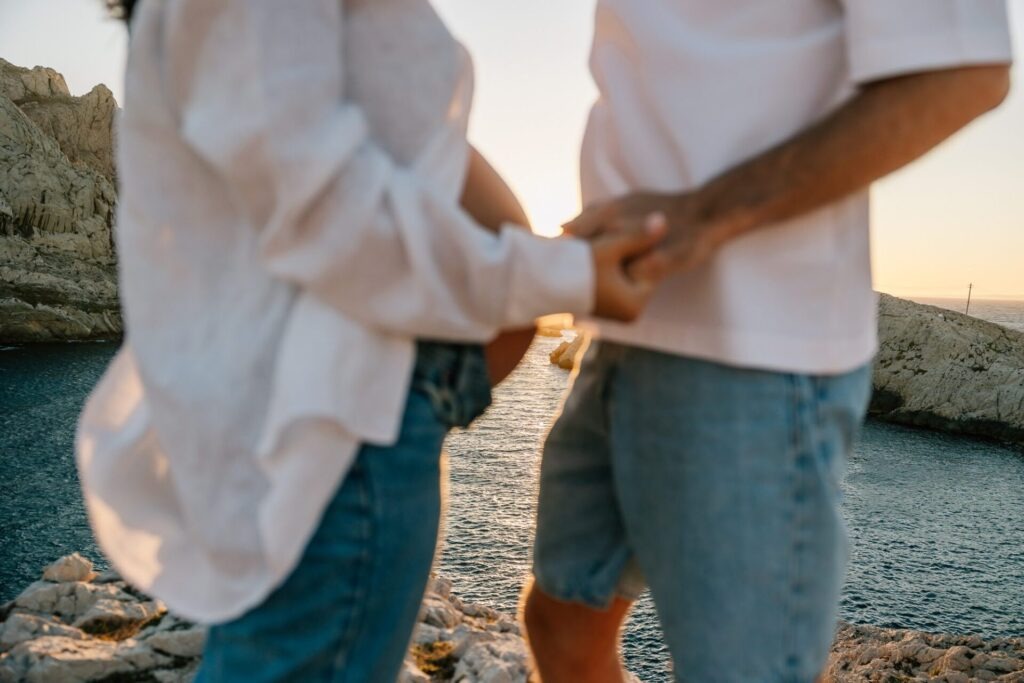 couple se tenant la main lors d'une séance photo grossesse au bord de la mer