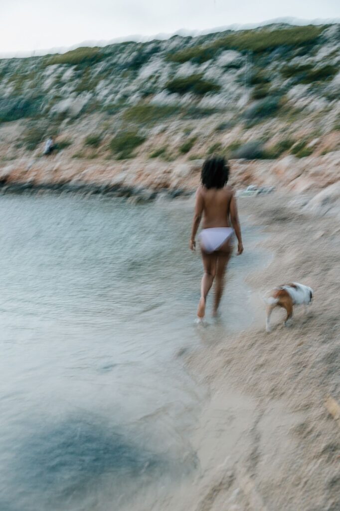 Femme enceinte marchant dans l’eau avec son chien lors d’une séance photo grossesse à la plage Marseille 13008