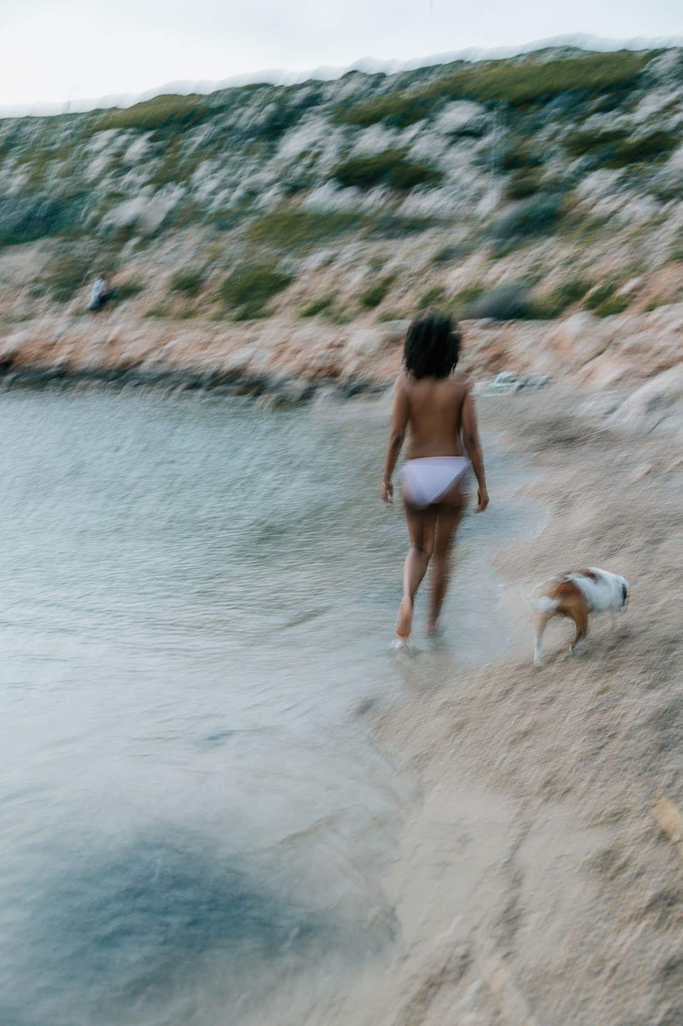 Femme enceinte marchant dans l’eau avec son chien lors d’une séance photo grossesse à la plage Marseille 13008