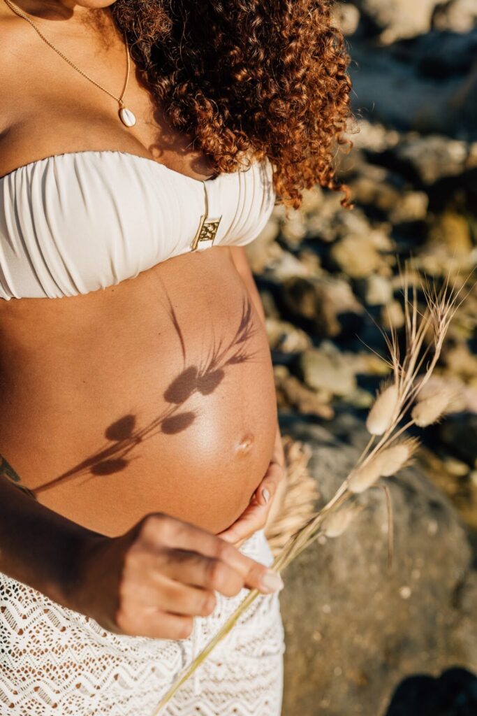 détail ventre femme enceinte avec ombre de plante séance photo grossesse à la plage