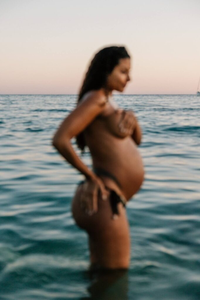 flou artistique - femme enceinte dans l’eau pendant une séance grossesse à la plage