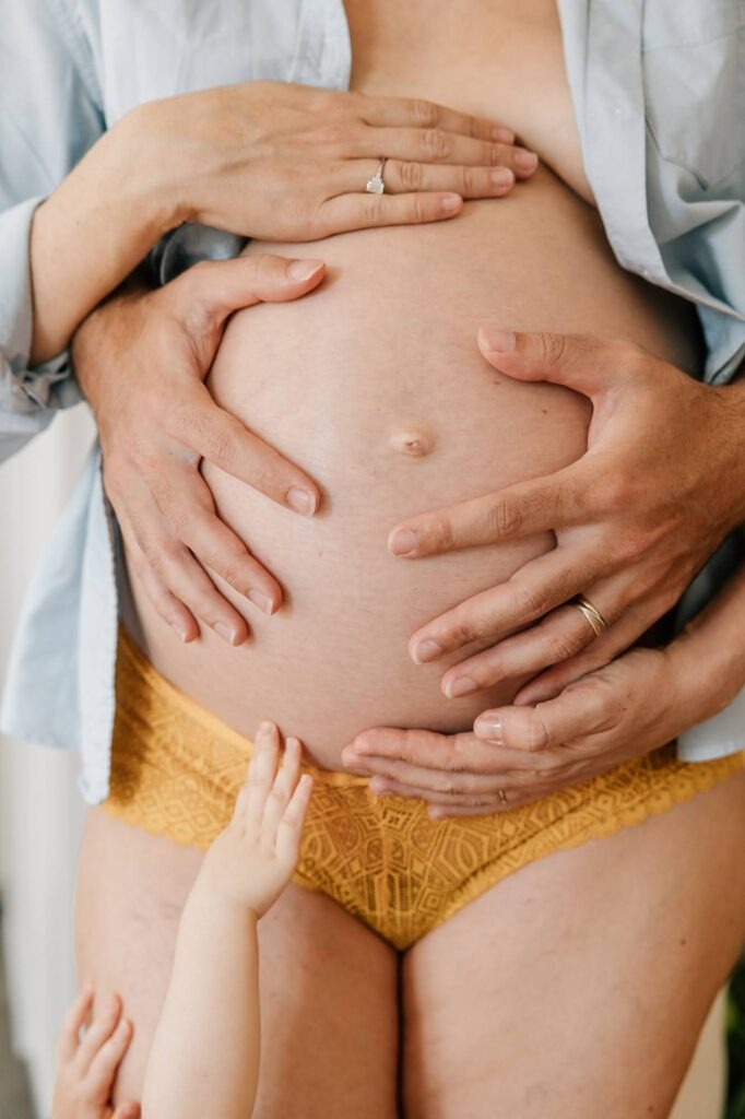 Mains du couple sur le ventre nu lors d'une séance photo de grossesse