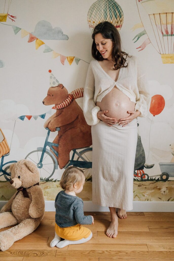 Femme enceinte en jupe claire dans une chambre d’enfant décorée lors d’une séance photo grossesse à domicile à Marseille