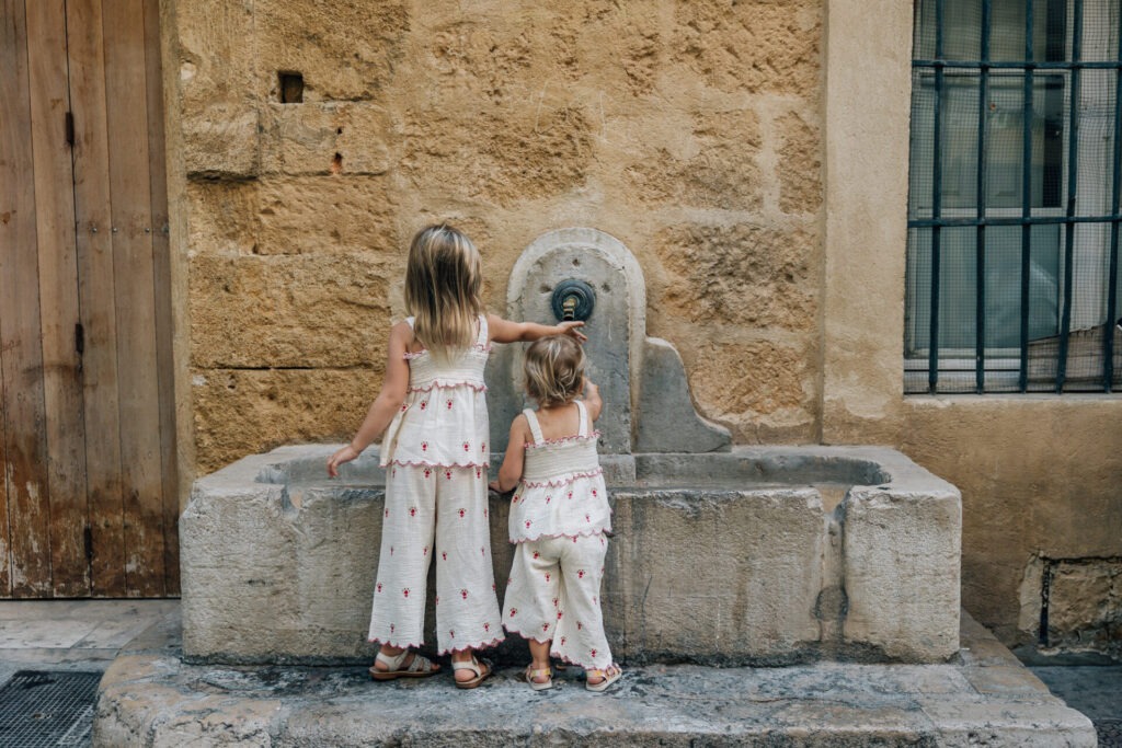 enfants jouant près d’une fontaine à aix en provence rue pavée séance photo famille