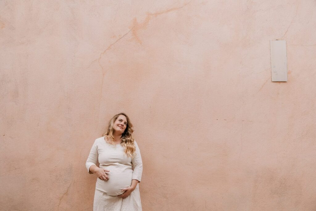 portrait de femme enceinte contre un mur pastel lors d’une séance photo grossesse à Cassis