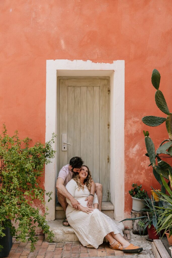 couple attendant un bébé assis devant une maison colorée à Cassis