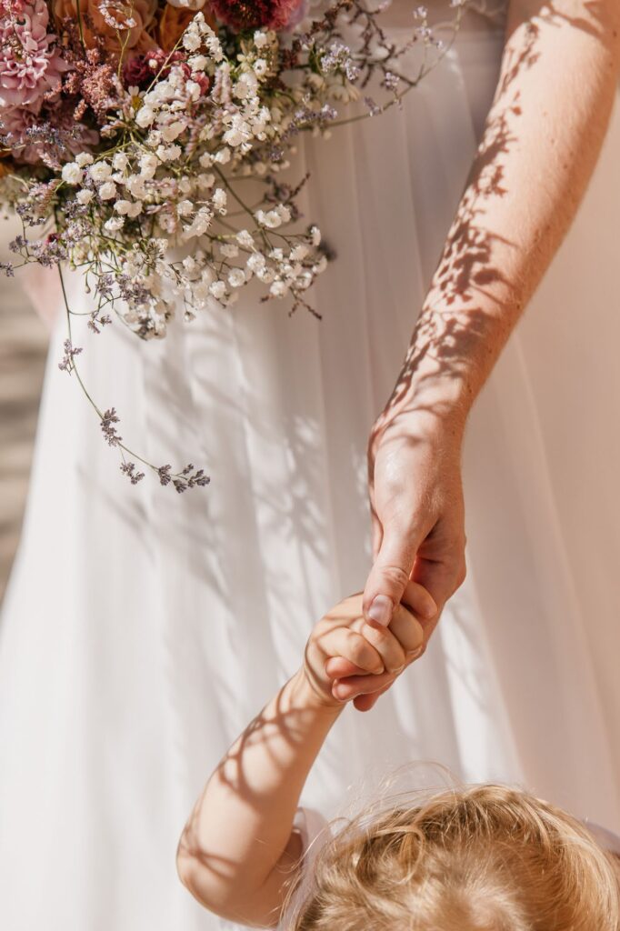 Détail des mains de la mariée tenant la main de son enfant pendant la préparation du mariage au château des Anglades à Hyères