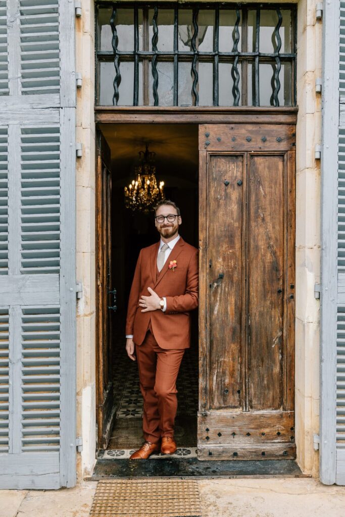 Portrait du marié pendant les préparatifs devant une porte ancienne – mariage en Provence