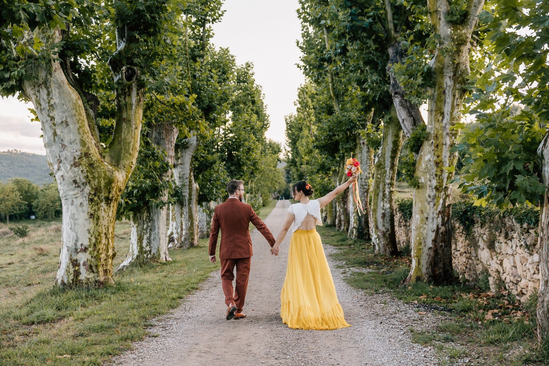 Couple de mariés dans une allée de platanes en Provence