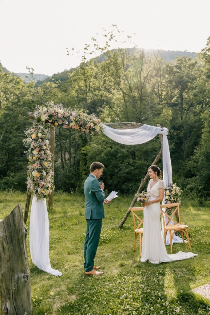 Cérémonie laïque en extérieur sous une arche fleurie lors d’un mariage dans la Drôme