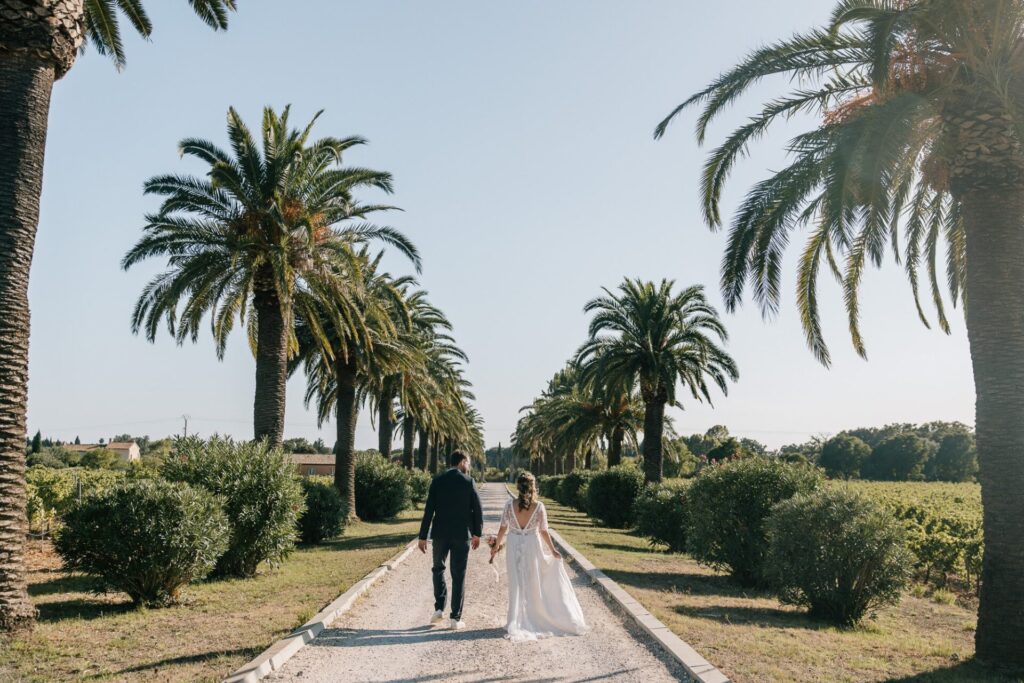Mariage au Château des Anglades dans le Var – couple dans l’allée bordée de palmiers