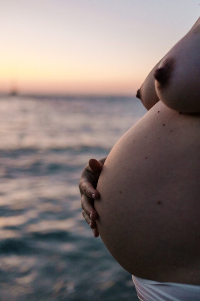 détail du ventre d’une femme enceinte face à la mer lors d’une séance photo grossesse à Marseille